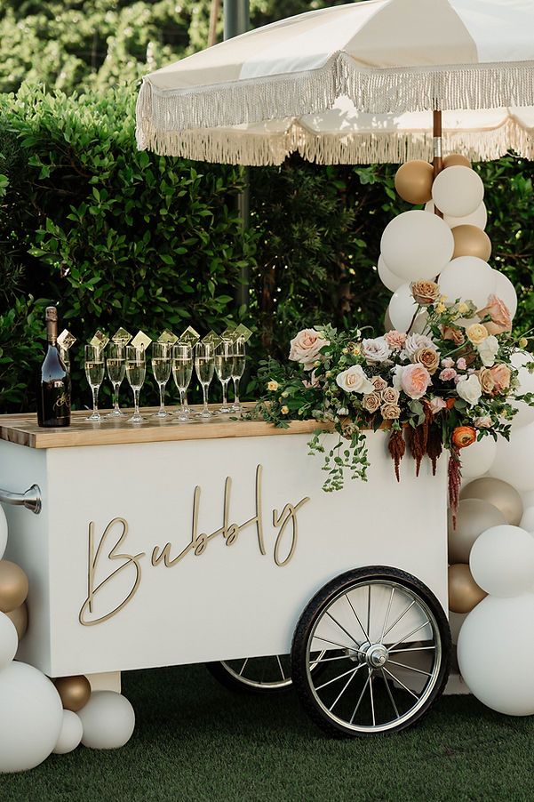 an ice cream cart decorated with balloons, flowers and wine glasses for a wedding reception