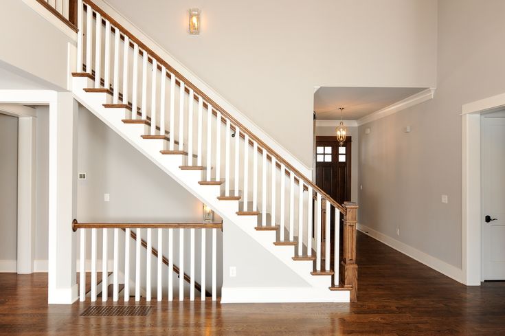 an empty room with stairs and hard wood floors