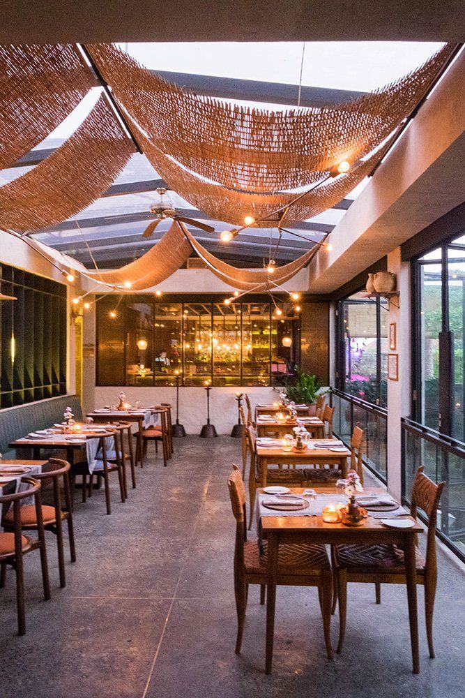 an empty restaurant with tables and chairs covered in straw coverings, lights hanging from the ceiling