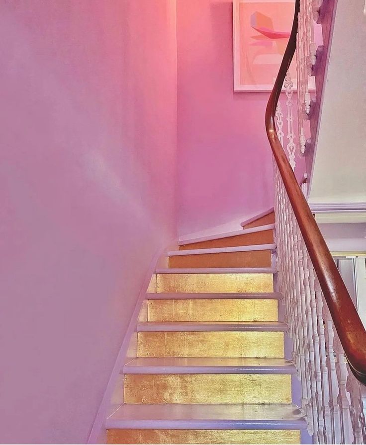 the stairs are painted pink and have wooden handrails that lead up to the second floor