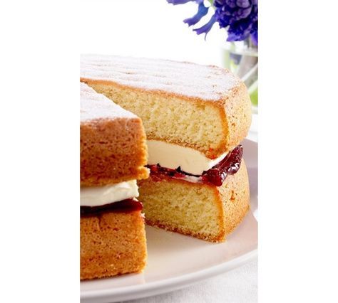 two pieces of cake sitting on top of a white plate next to a vase with purple flowers