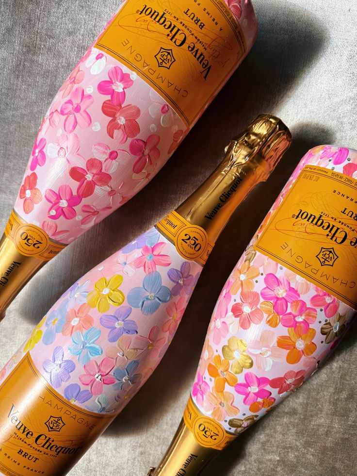 two bottles of champagne with flowers painted on them