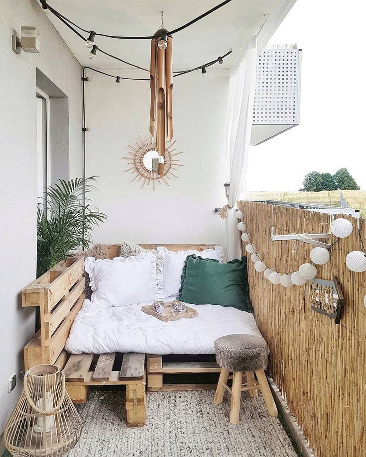 a bed made out of wooden pallets on top of a roof with string lights hanging from the ceiling