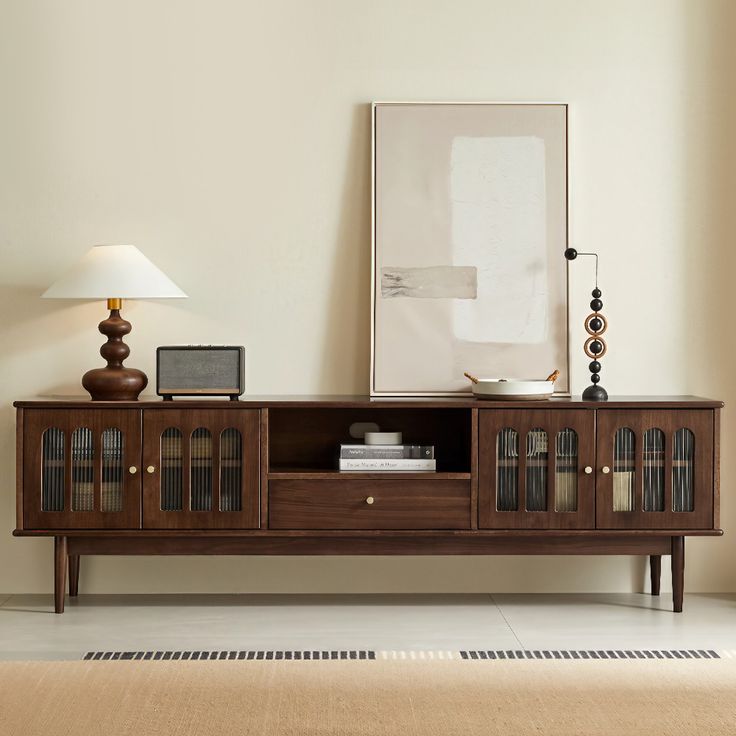 a living room with an entertainment center, lamp and pictures on the wall above it