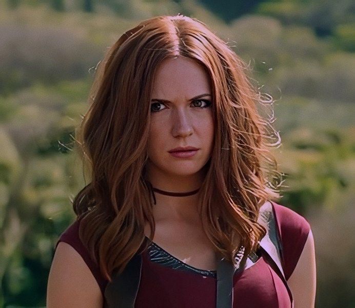 a woman with long red hair wearing a leather vest