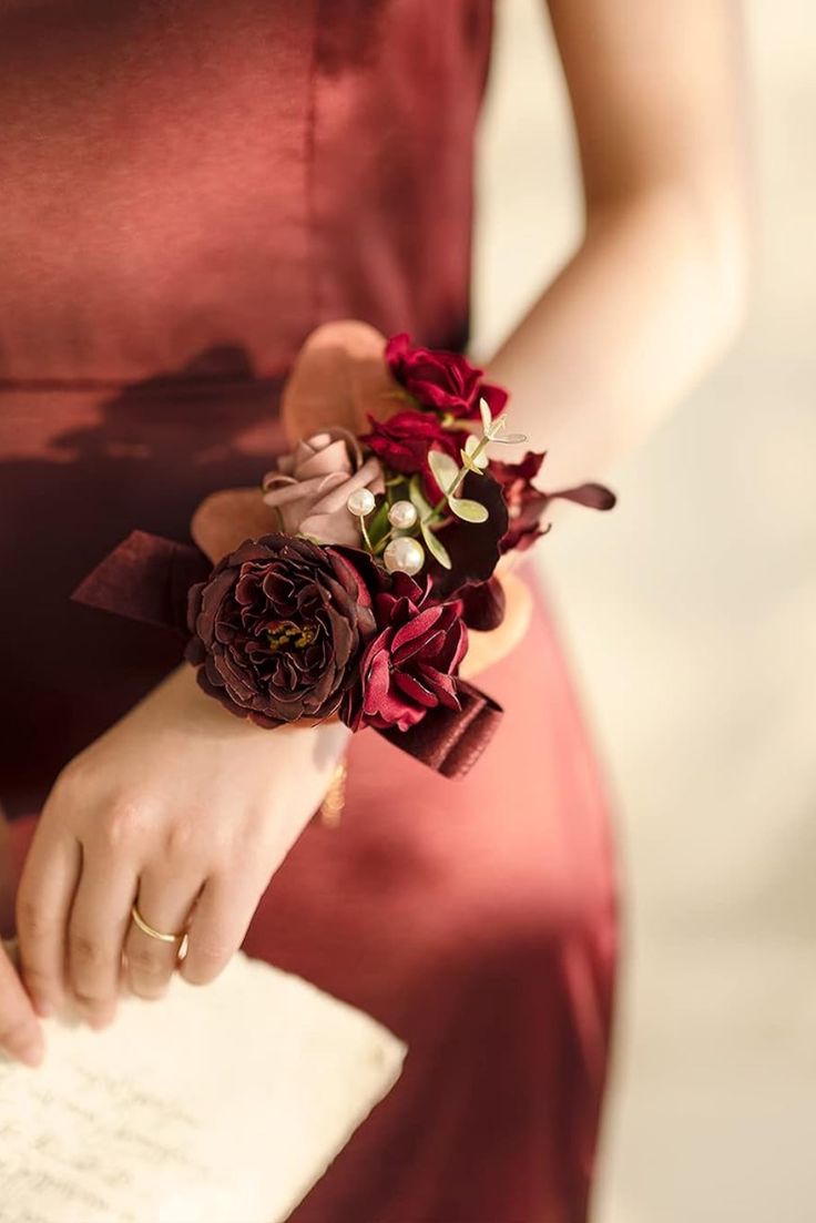 a close up of a person wearing a red dress and holding a paper with flowers on it