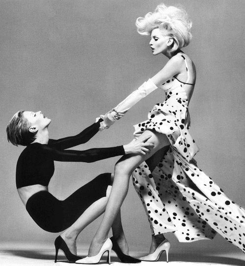 two women in black and white dresses are touching each other's legs with their hands