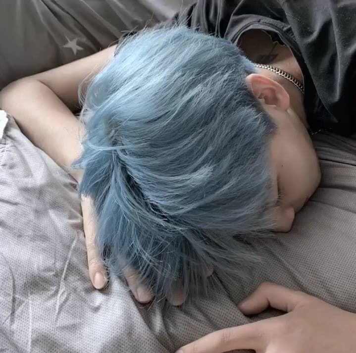 a person with blue hair laying on a bed