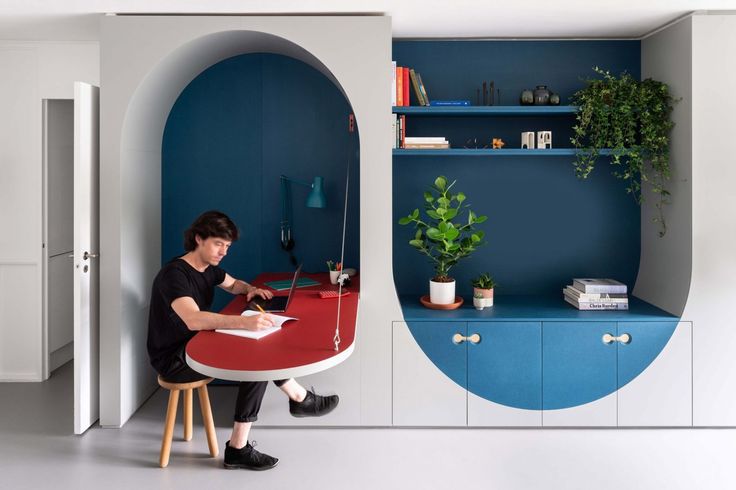 a man sitting at a table in front of a blue and white wall with an oval design on it