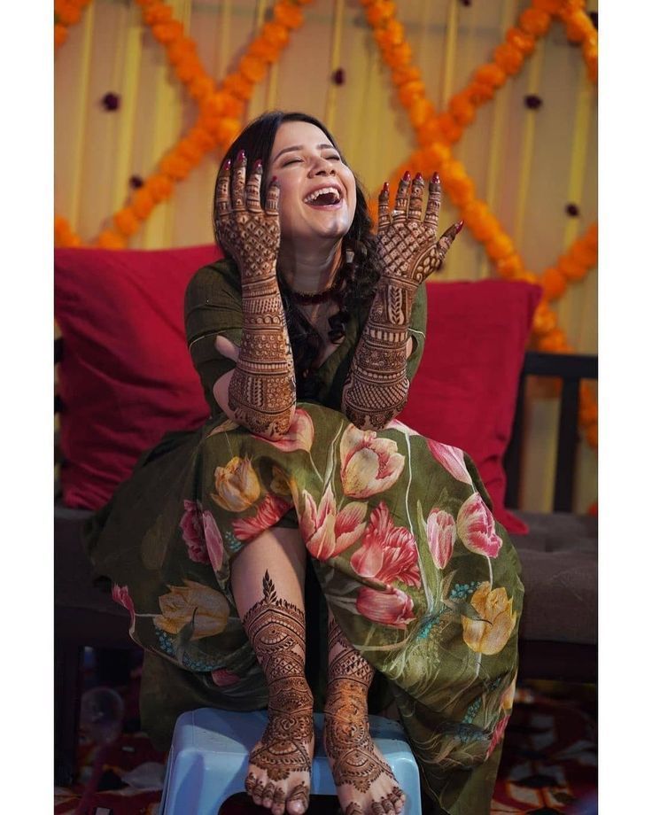 a woman sitting on top of a blue stool with her hands up in the air