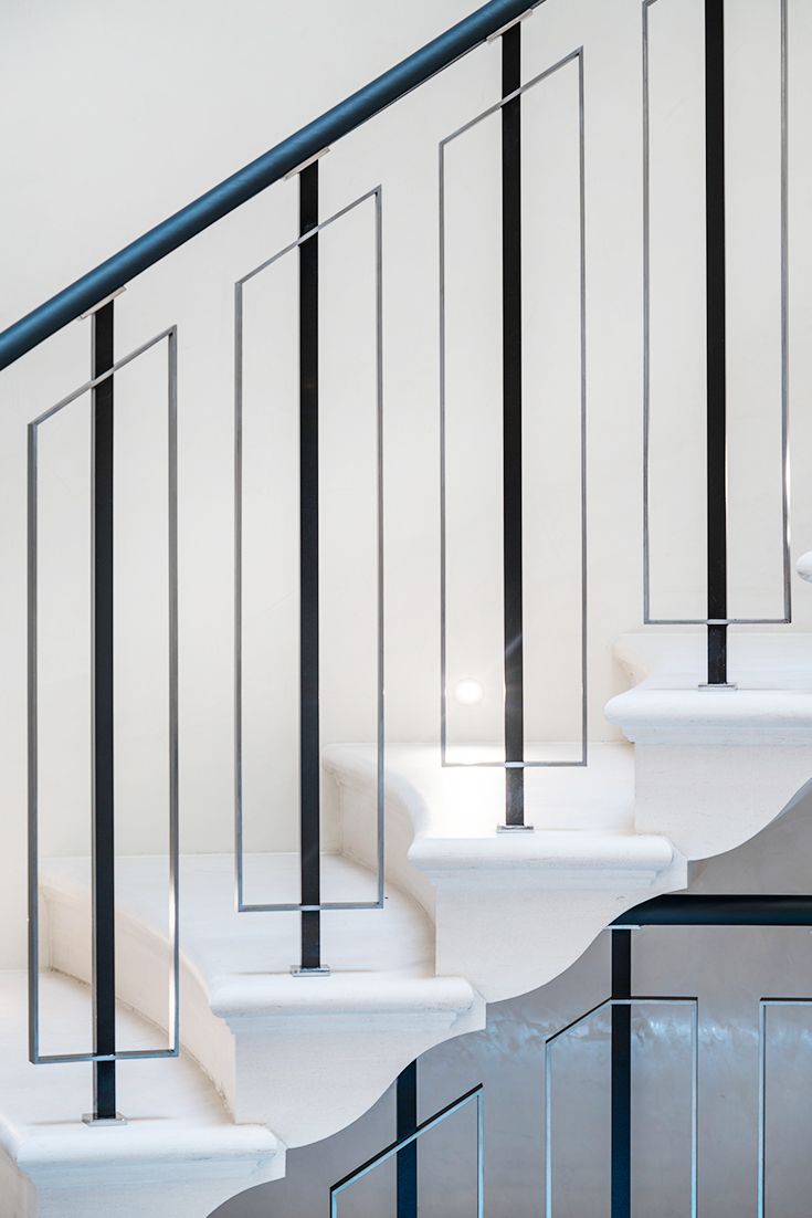 a white staircase with black handrails and glass railing