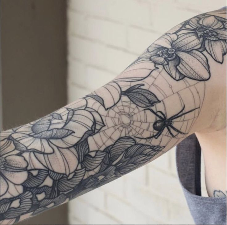 a woman's arm with flowers and spider web tattoo design on the left arm