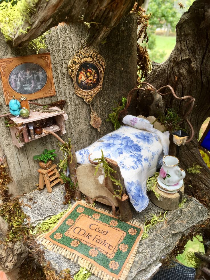 a doll house with furniture and decorations on the ground in front of a tree trunk