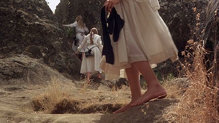 a woman in a white dress is standing on some rocks