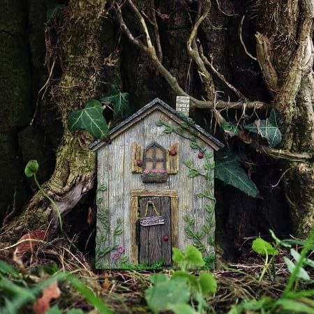 a small wooden house sitting in the middle of a forest next to a large tree