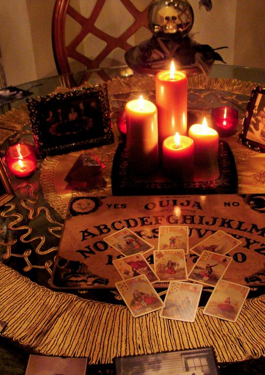 a table topped with cards and candles on top of a cloth covered table next to pictures