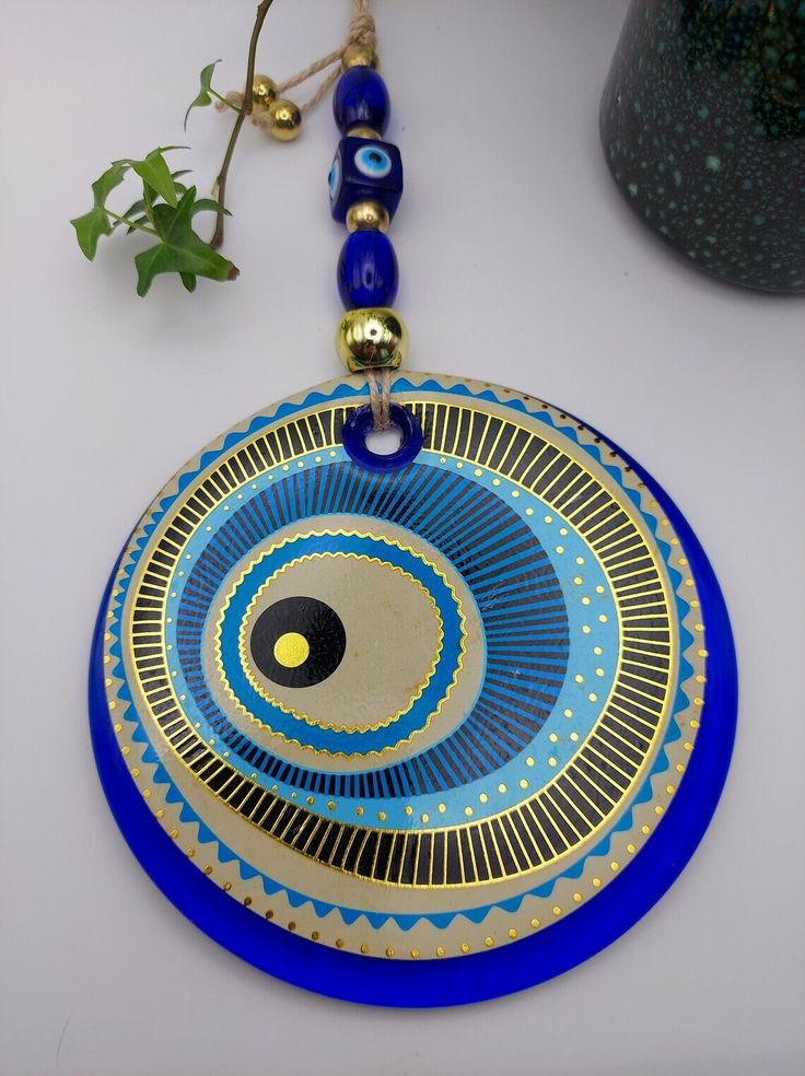 a blue and gold plate sitting on top of a table next to a potted plant