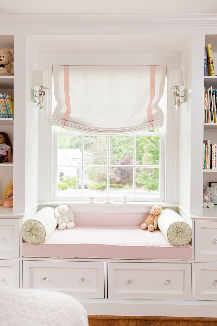 there is a window seat in the room with bookshelves and stuffed animals on it