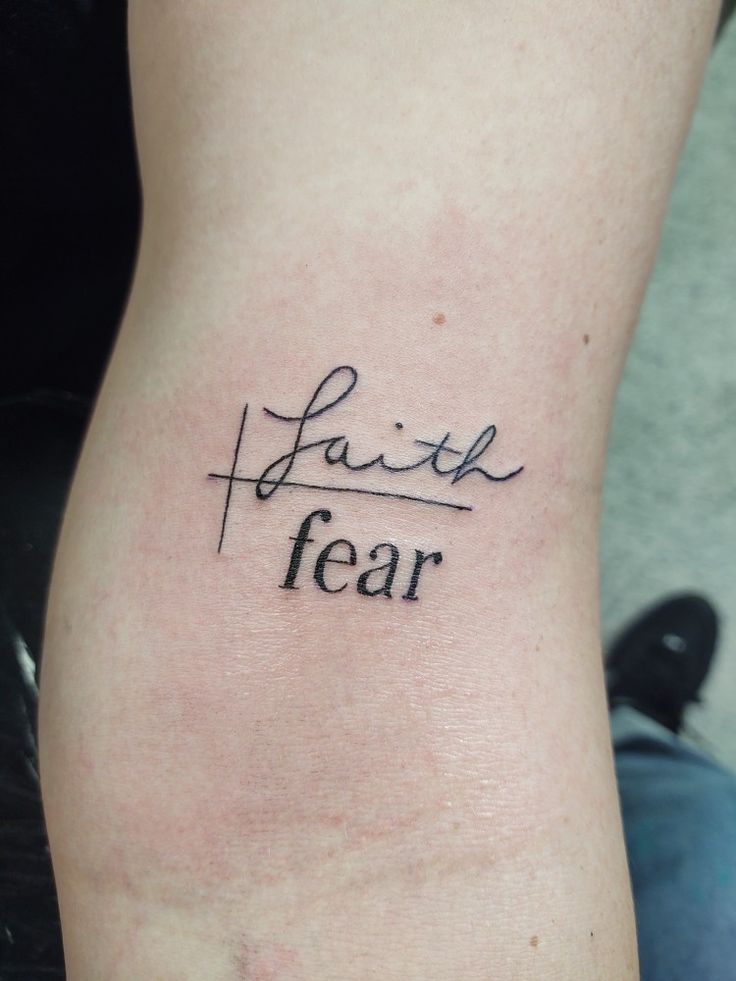 a person with a tattoo on their leg that says faith and fear in cursive writing