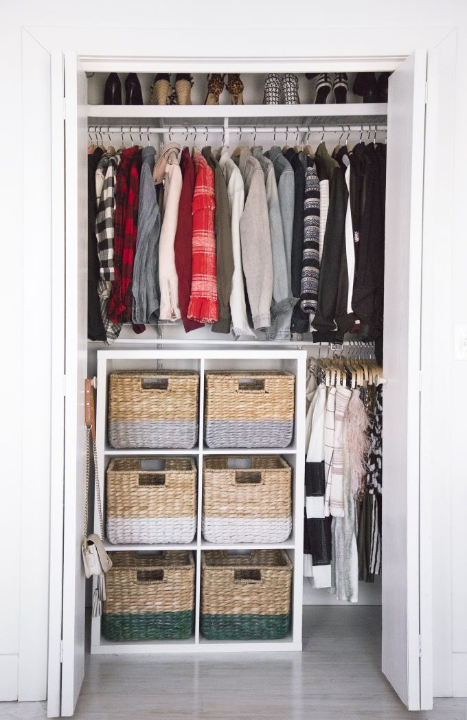 an organized closet with baskets and clothes