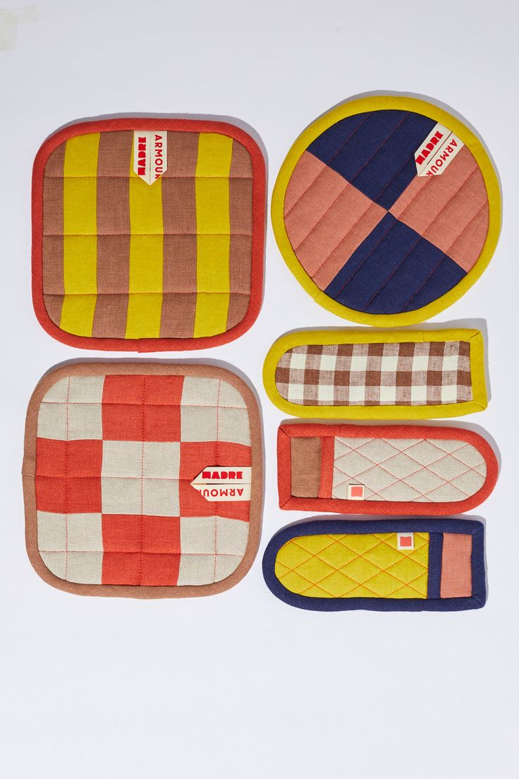 four oven mitts and one pot holder in various colors, including red, yellow, blue, and white