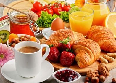 the breakfast is ready to be eaten on the wooden table with fresh fruit, coffee and croissants