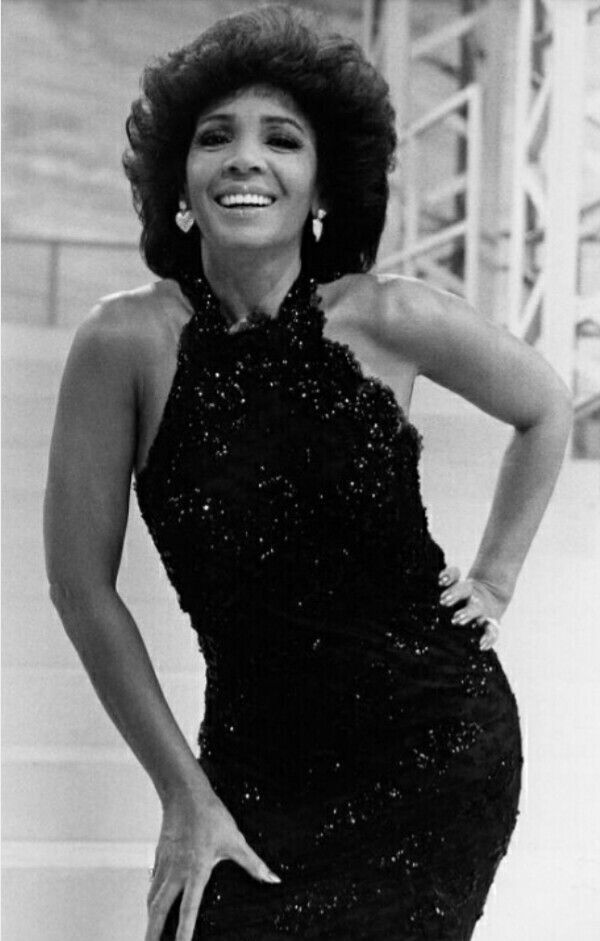 an old black and white photo of a woman in a dress posing for the camera