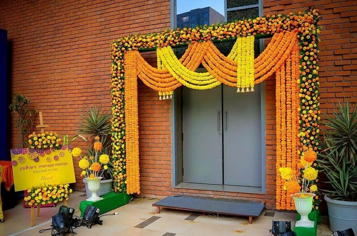 an entrance to a building decorated with flowers and yellow garlands on the front door