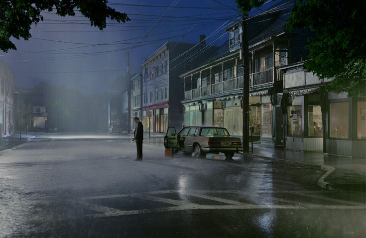 a man standing in the middle of a street at night with an umbrella over his head