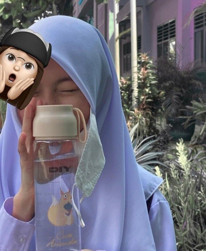 a woman wearing a blue hijab holding a bottle with a monkey on it