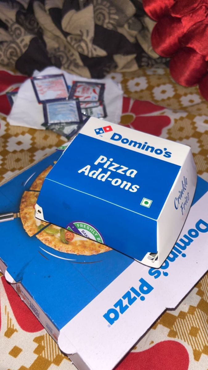 a pizza box sitting on top of a table next to a red and white pillow