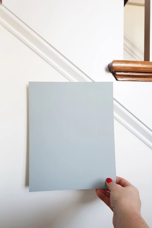 a person holding up a square piece of paper in front of a stair rail and handrail