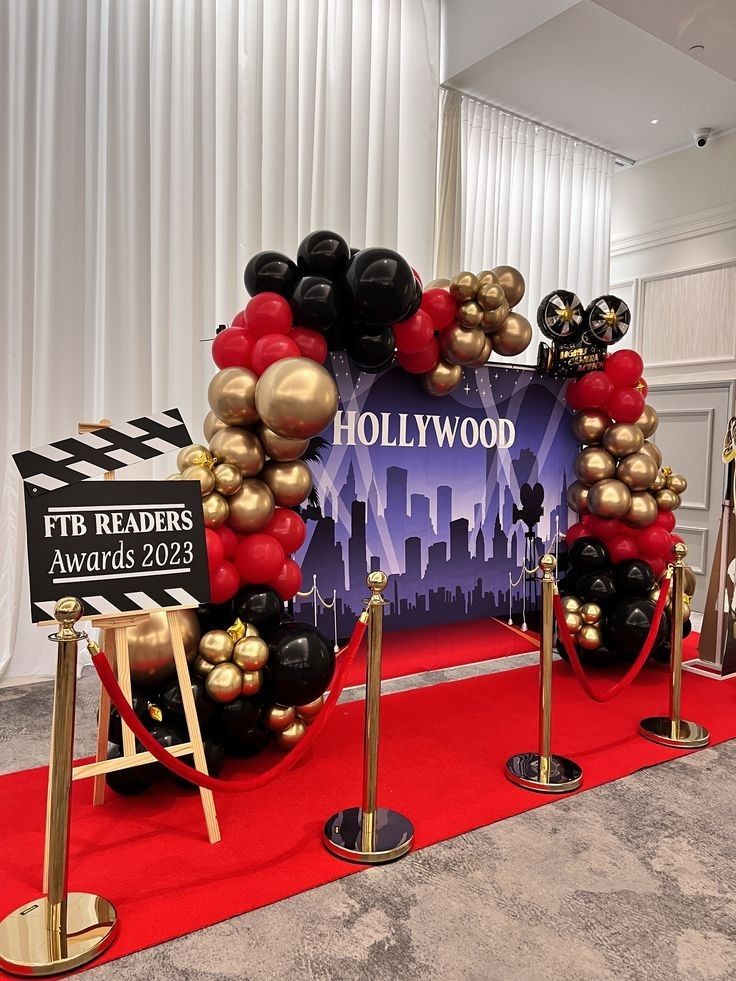 hollywood balloon arch on red carpet with black and gold balloons