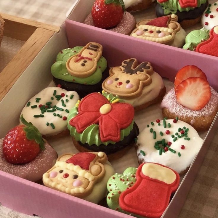 there are many decorated cupcakes in the box on the table and one has a strawberry