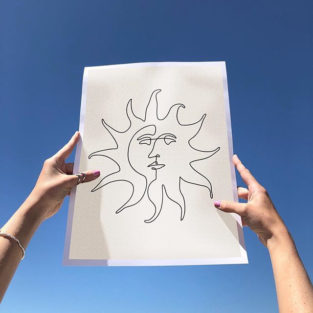 two hands holding up a piece of paper with the sun drawn on it