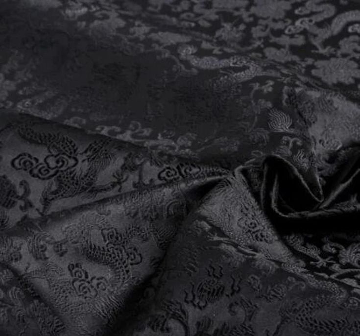 an image of black and silver fabric with floral design on the bottom, close up