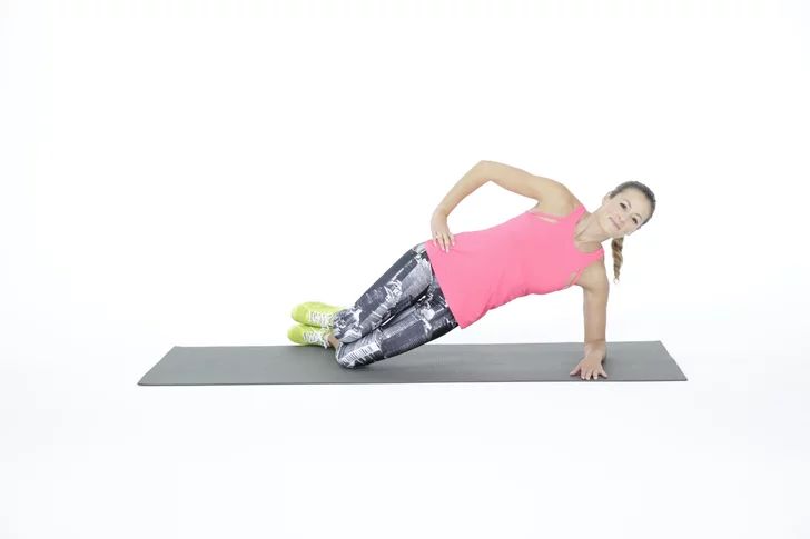 a woman in pink shirt doing push ups on yoga mat