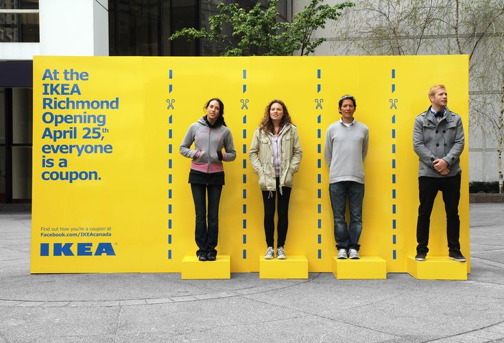 three people standing in front of a yellow wall with the ikea logo on it