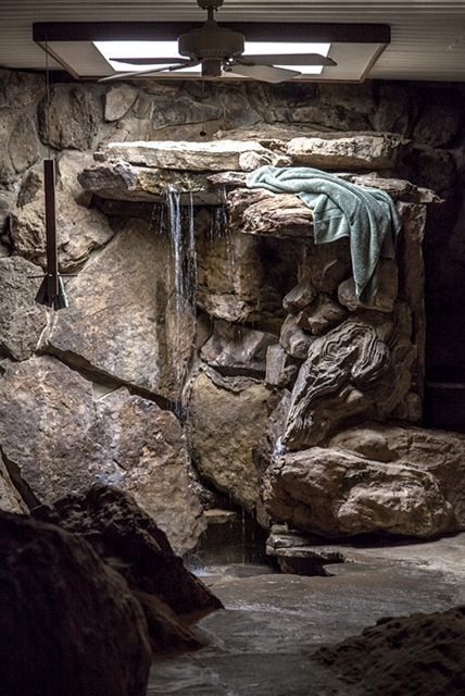 there is a waterfall in the middle of this room with rocks and water running down it