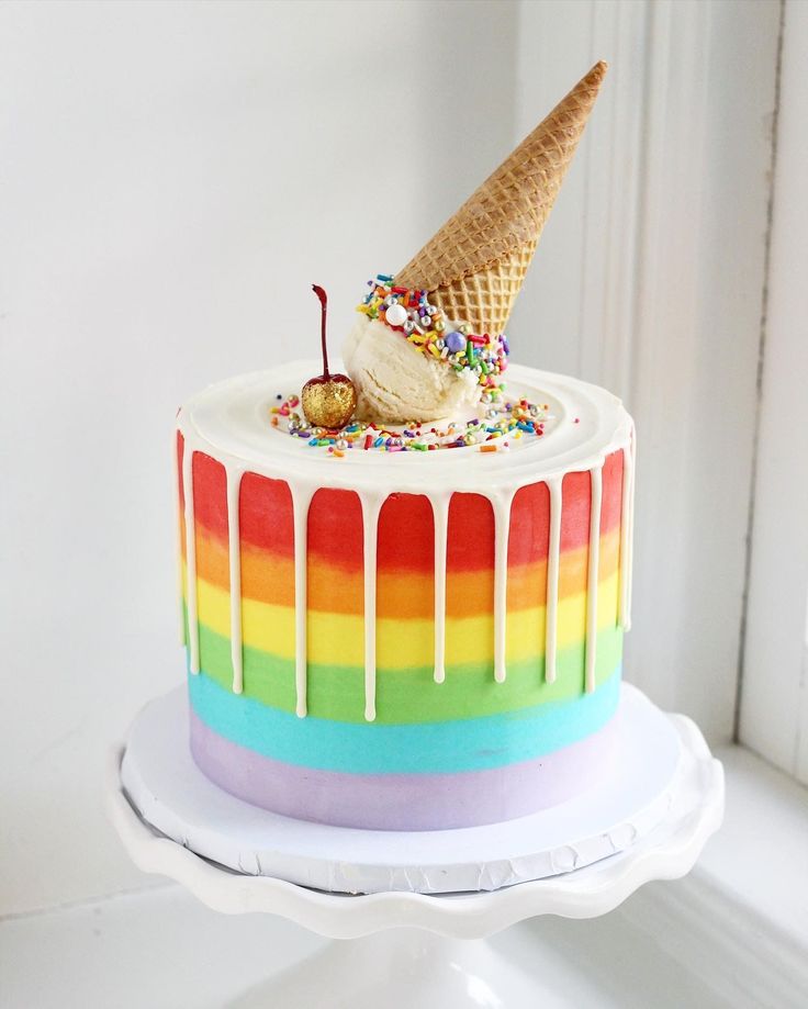 a rainbow cake with an ice cream cone on top