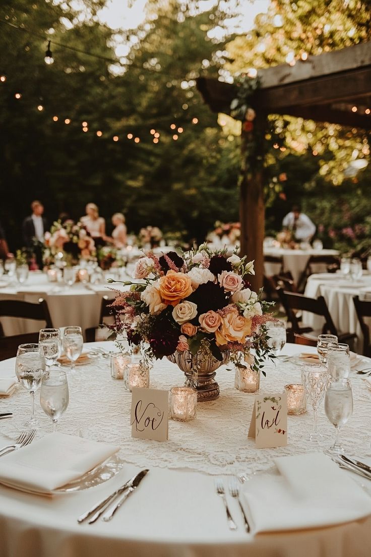 a table with candles and flowers on it at a wedding reception in an outdoor setting