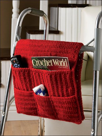 a crocheted red bag hanging from a metal frame with two pockets on it