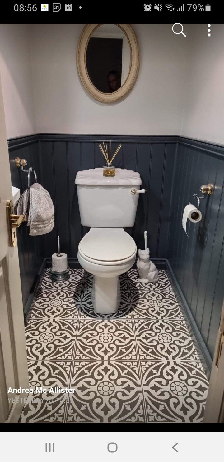 a white toilet sitting inside of a bathroom next to a mirror on the side of a wall