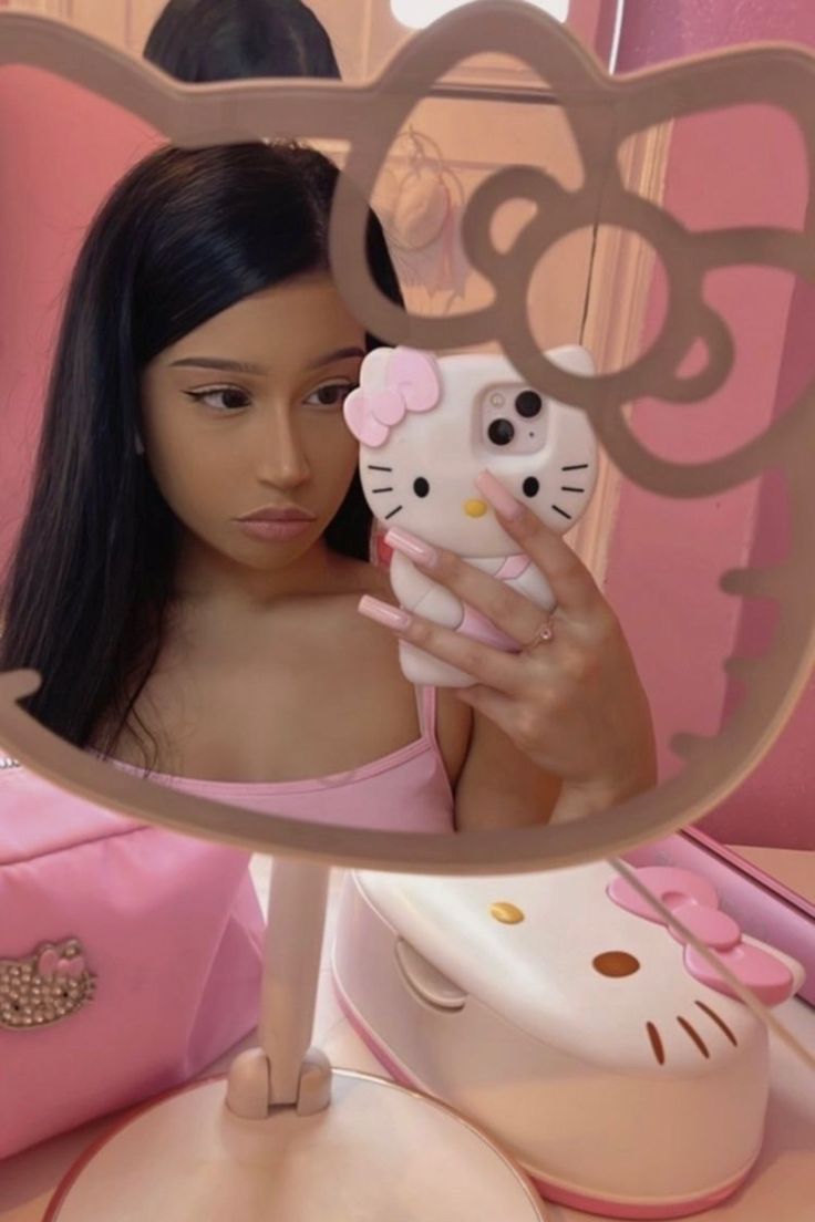 a woman taking a selfie in front of a mirror with hello kitty on it