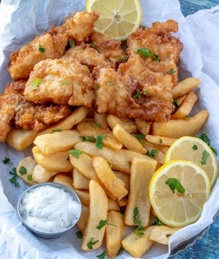 fried fish and fries with lemon wedges on the side