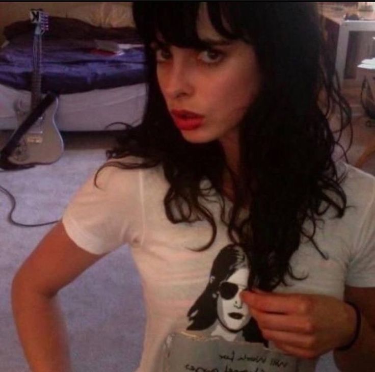 a woman with long black hair wearing a t - shirt and holding a cell phone