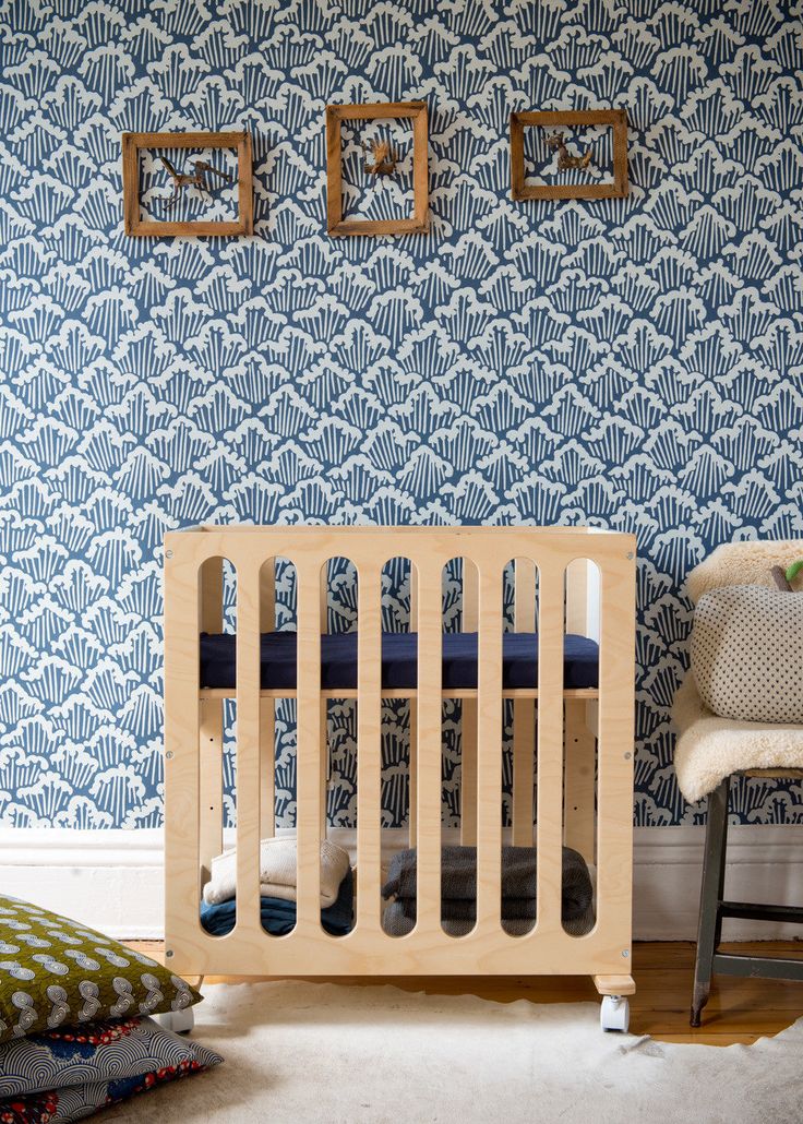 a baby crib in the corner of a room with blue and white wallpaper