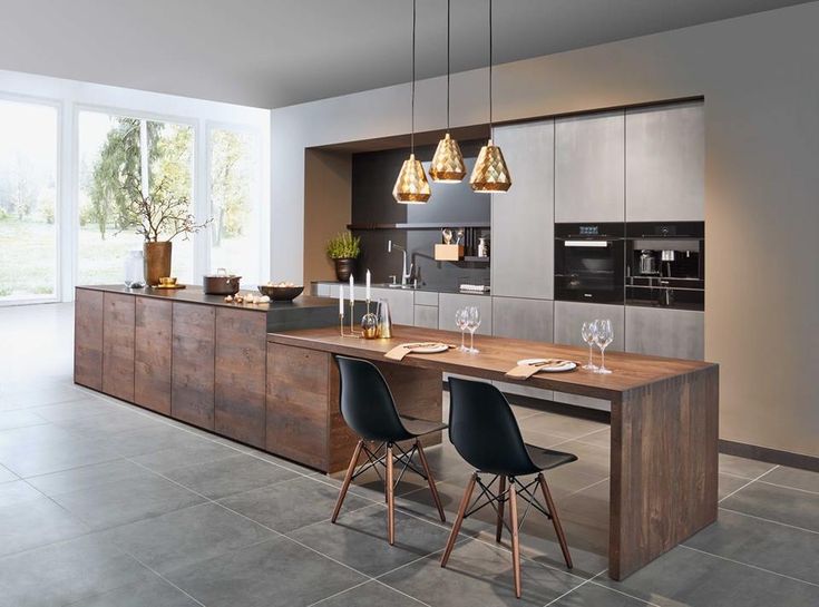 a modern kitchen with an island and dining table in the center, surrounded by black chairs