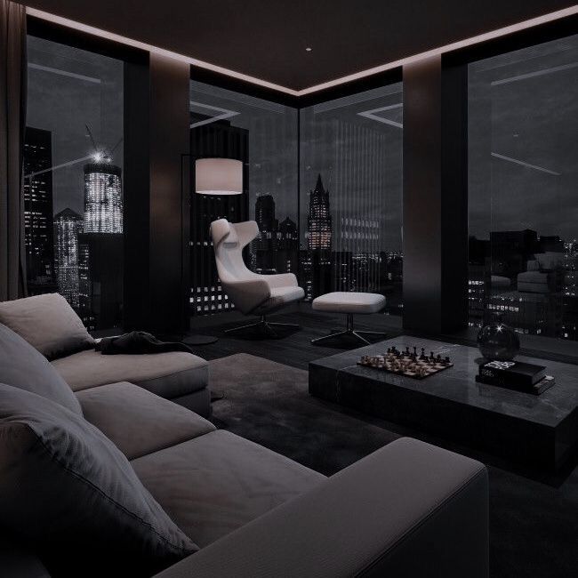 a living room filled with furniture and a view of the city at night from across the room