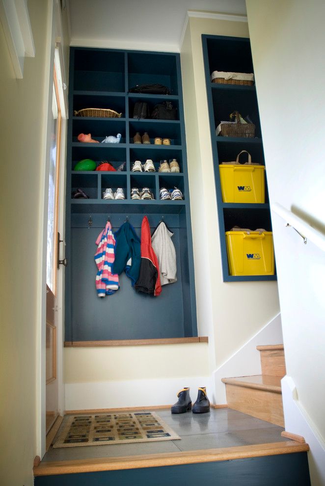 an entry way with blue shelves and shoes on the stairs, next to a yellow bin